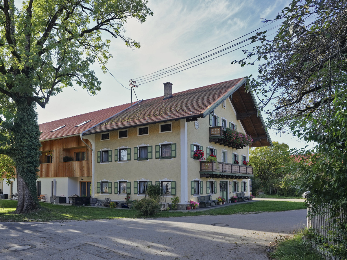 Ein zweistöckiges Haus mit Holzfassade, links ist eine Garage angebaut.
